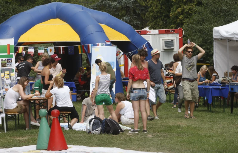 a large group of people gather in front of an inflatable arch at a festival