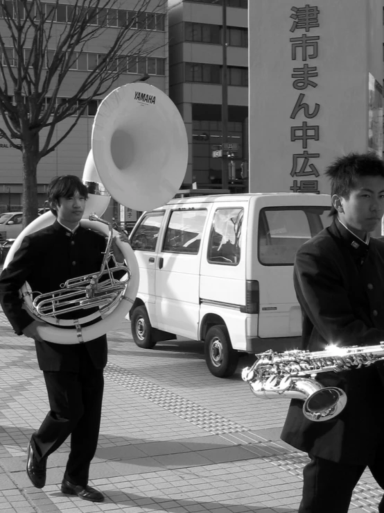 two men on a busy street are carrying sound equipment