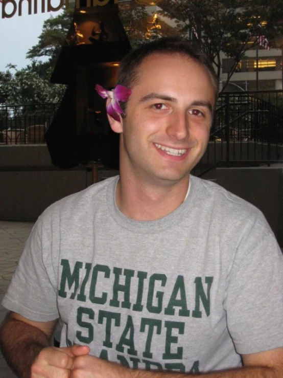 a man holding up a pink flower in the hair