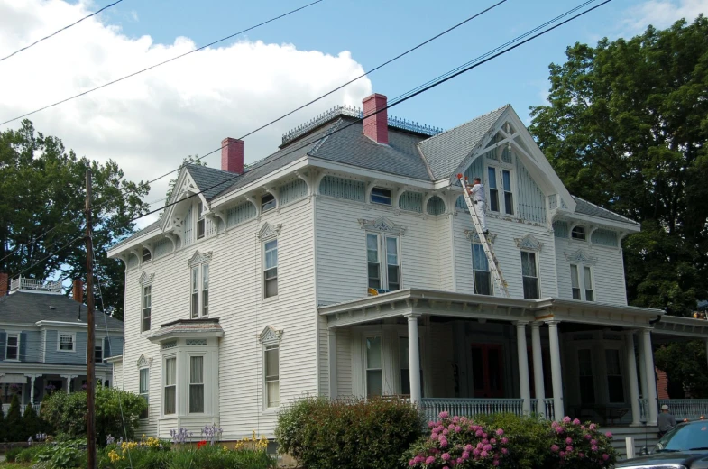 large victorian styled white house sits under blue skies