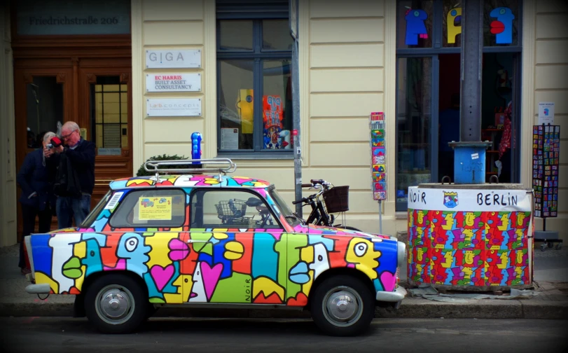 colorful art painted car parked on street next to building
