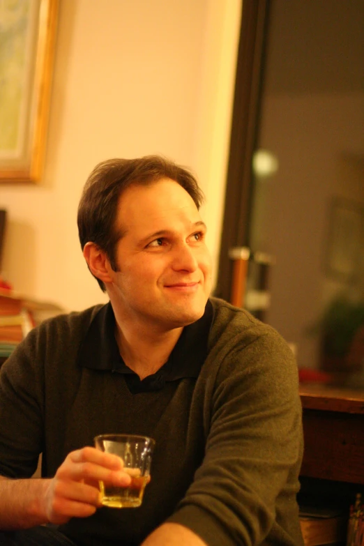 a man smiling and holding a glass of wine