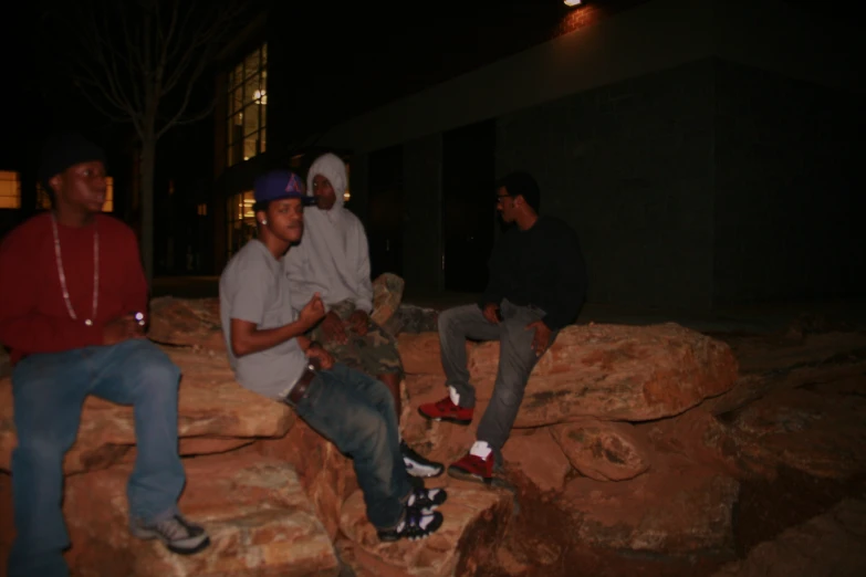 three guys on the edge of some rocks at night