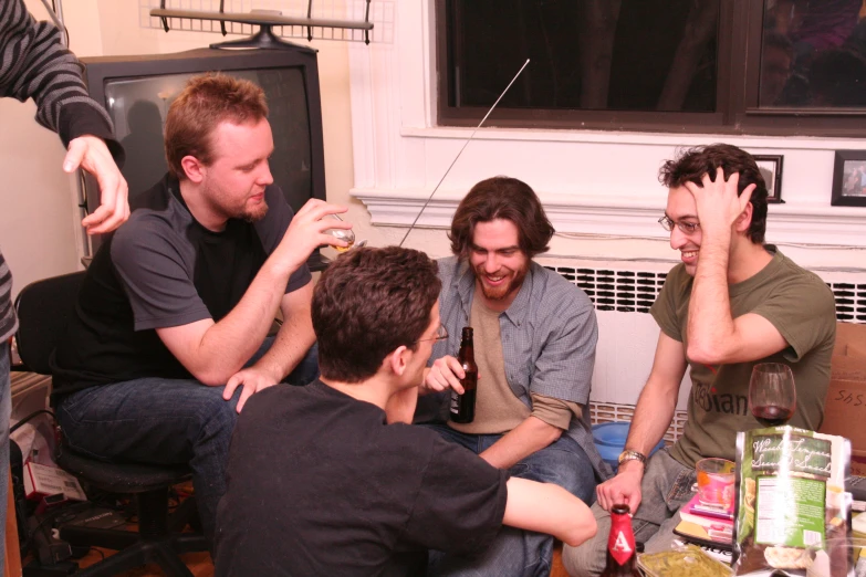 three men sit around the table talking and drinking