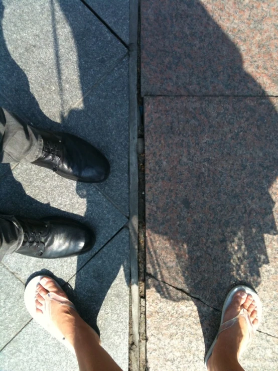 two feet and a persons shadow on concrete