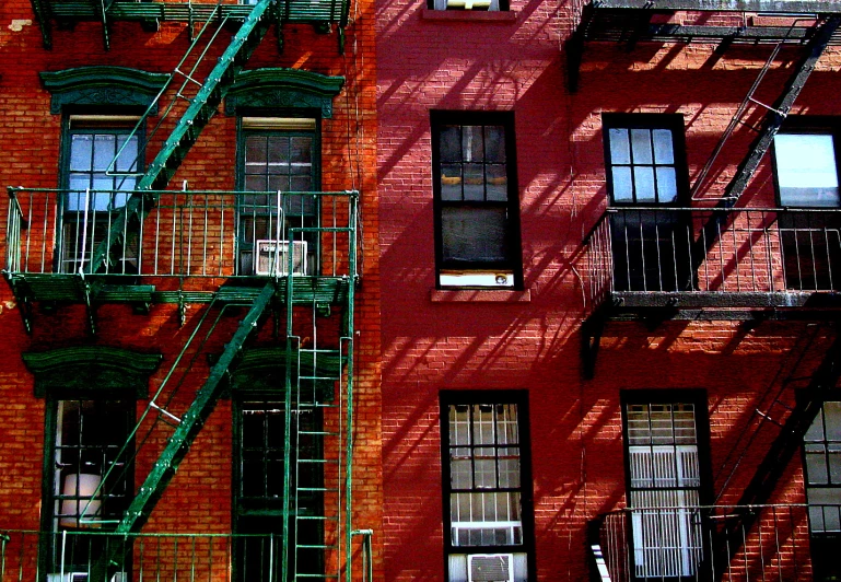 the facade of an apartment building with fire escapes and a green staircase on each side