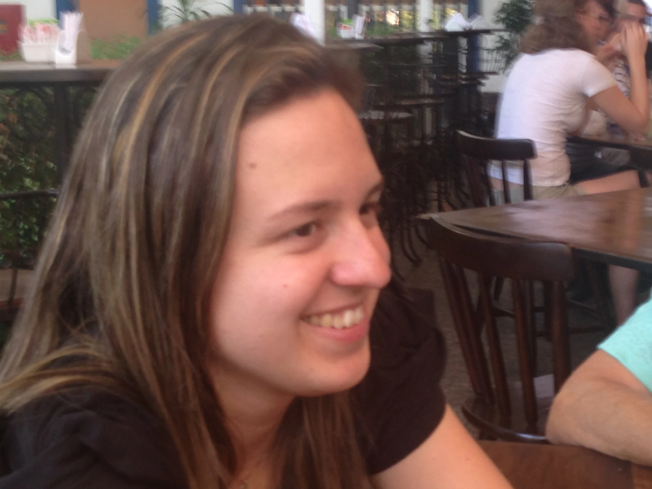 girl sitting down smiling, in front of table with books