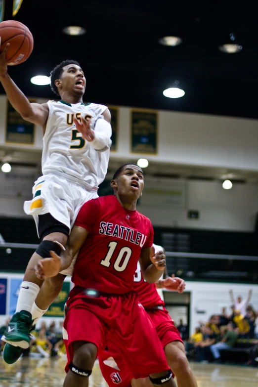 two men on opposing teams, one with a basketball and the other holding a basketball