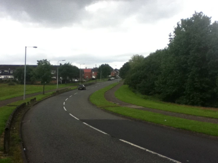 the view of a curve in a road leading into a village