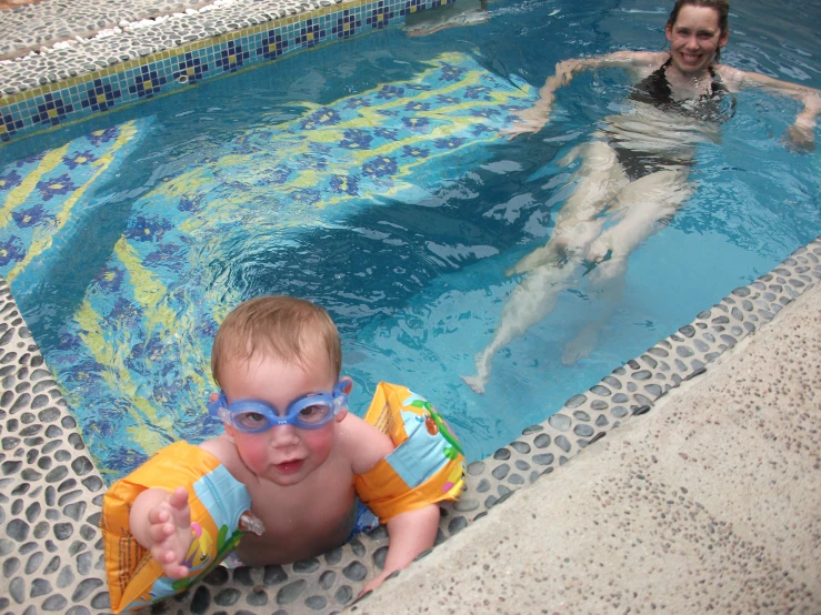 a small baby is in a pool with swimming goggles on