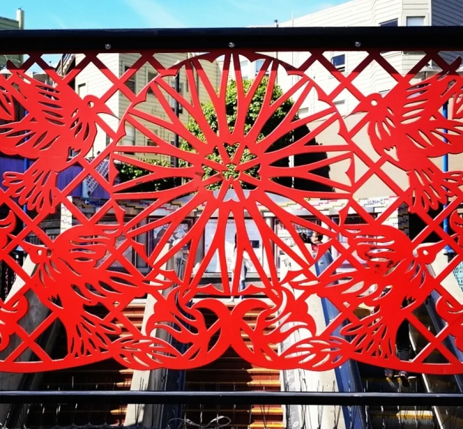 a large red metal sculpture with designs behind it