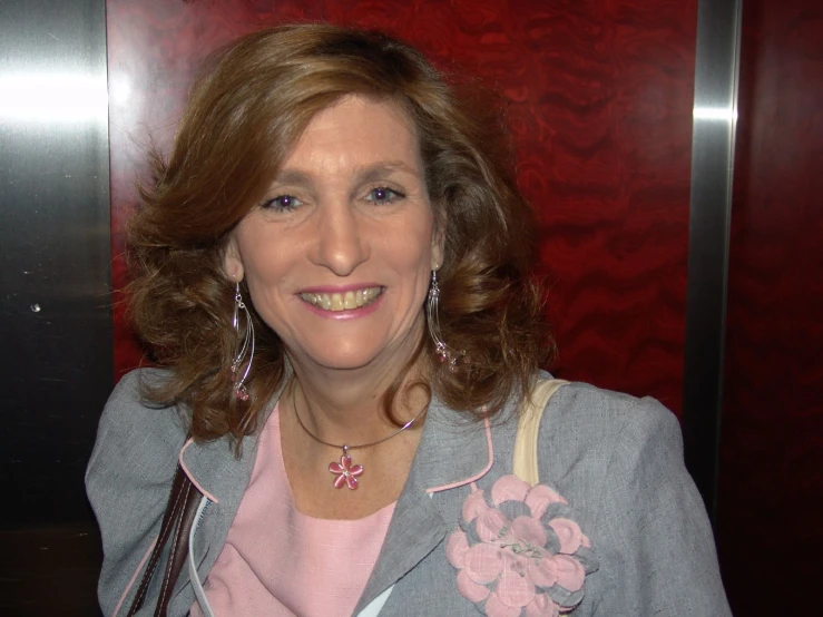 a smiling woman wearing silver and pink, with an umbrella in hand