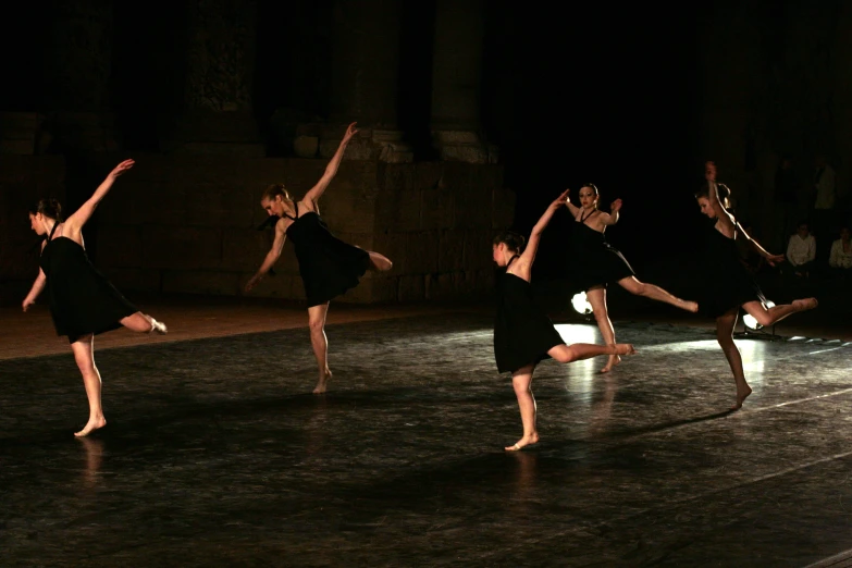dancers in black are standing on their feet, with arms raised