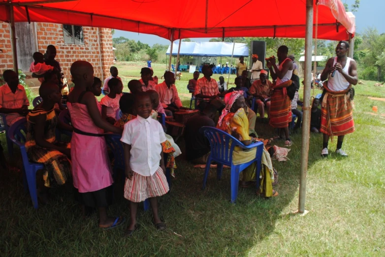 a group of children under a tent under a red umbrella