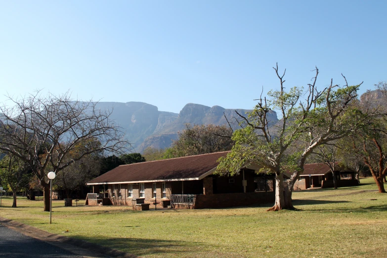 some trees bushes grass a building and mountains