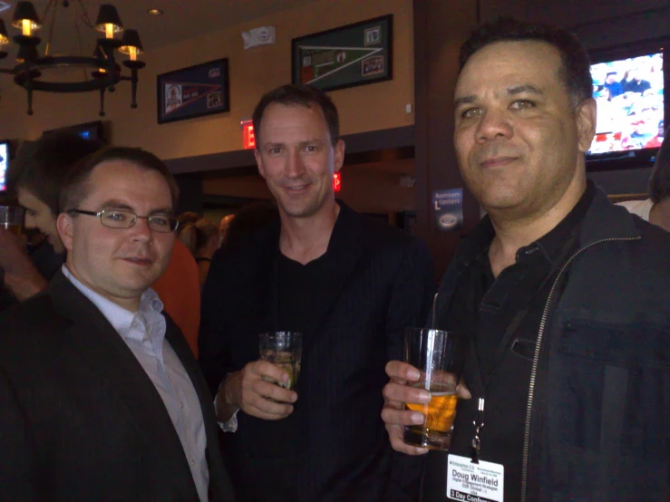 three men are standing next to each other with drinks