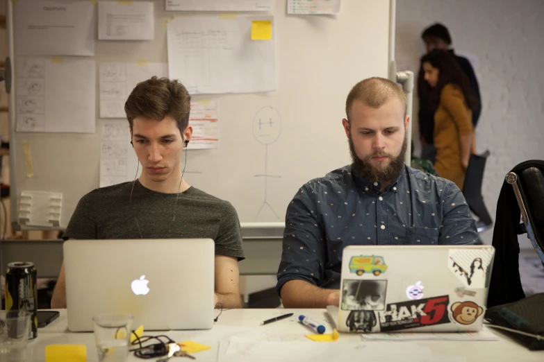 two men sitting together on a laptop computer