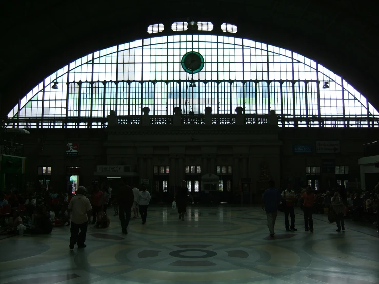 large building with glass ceilings, several people and a few clocks