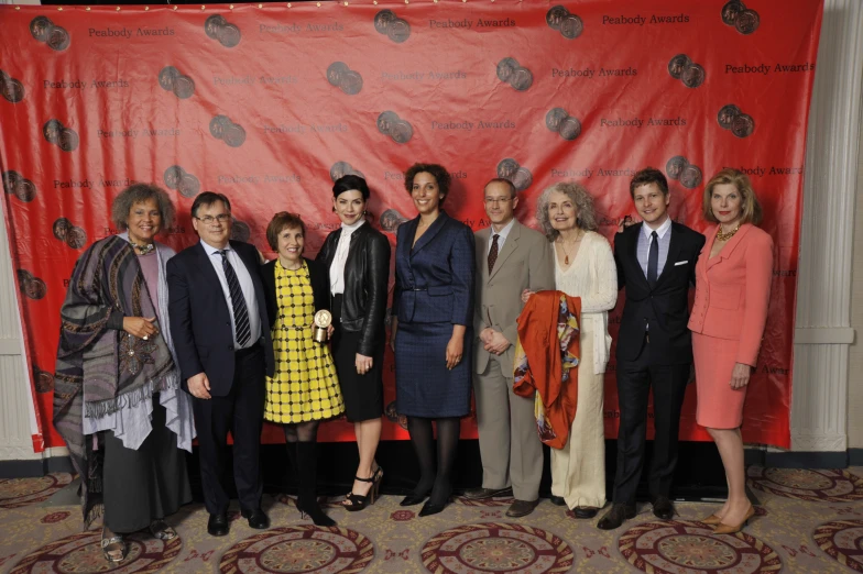 a large group of people standing together in front of a red wall