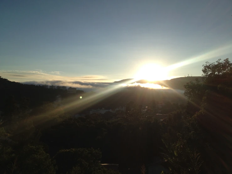 the sun shining over mountains with low lying fog in the distance