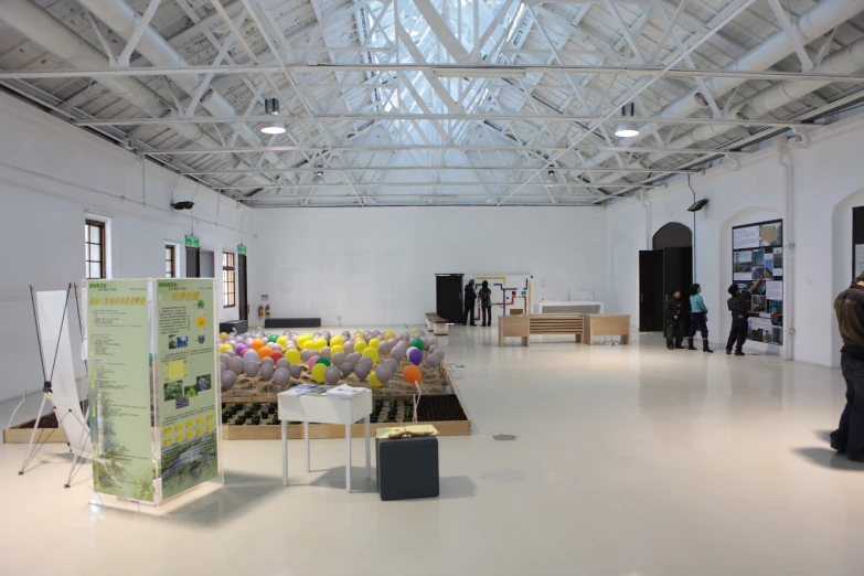 several white tables in an open room with several black tables and two white walls