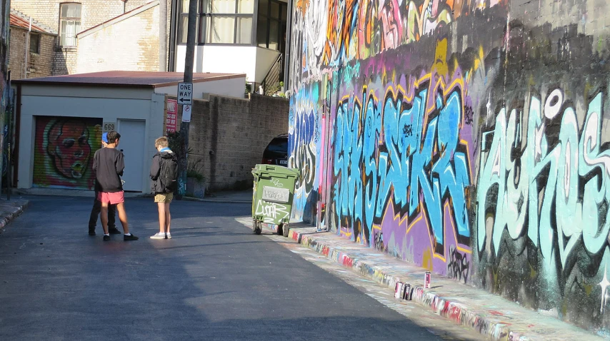 graffiti on the wall next to two people walking down the sidewalk