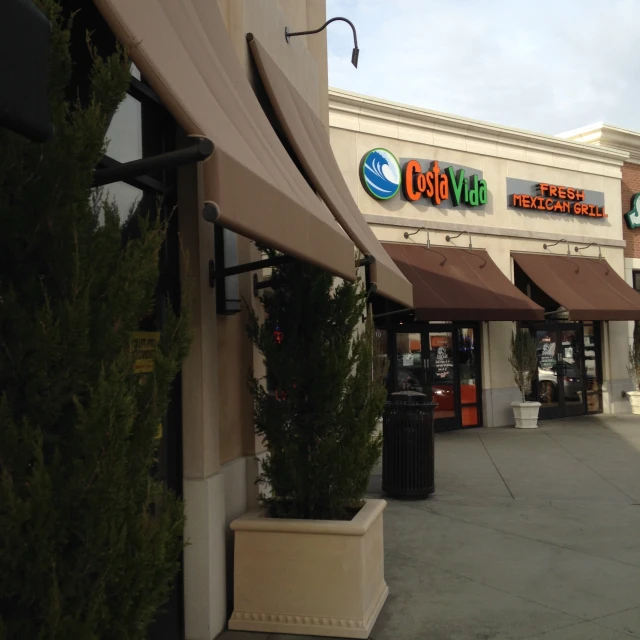 the front of a large grocery store with large green trees and bushes