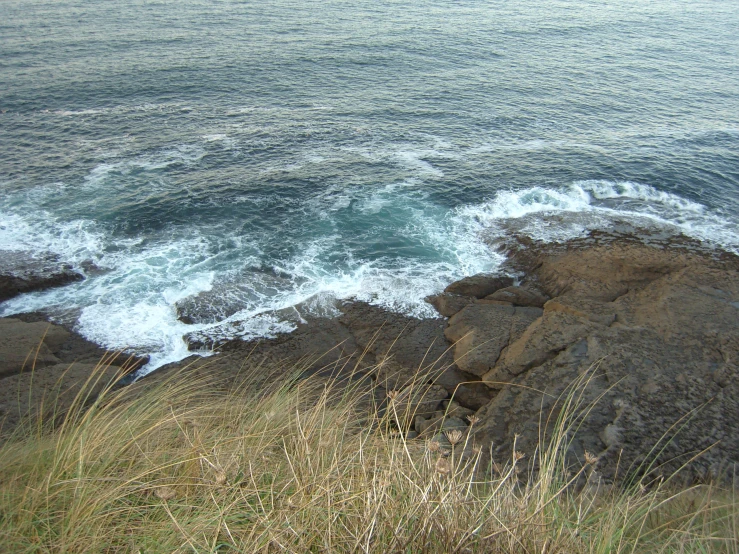 a man sitting on top of a hill next to the ocean