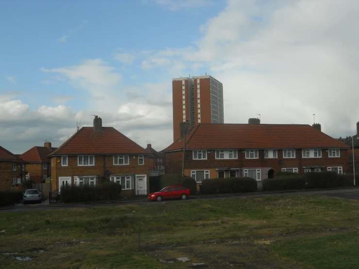 a brown brick building and grass with some clouds