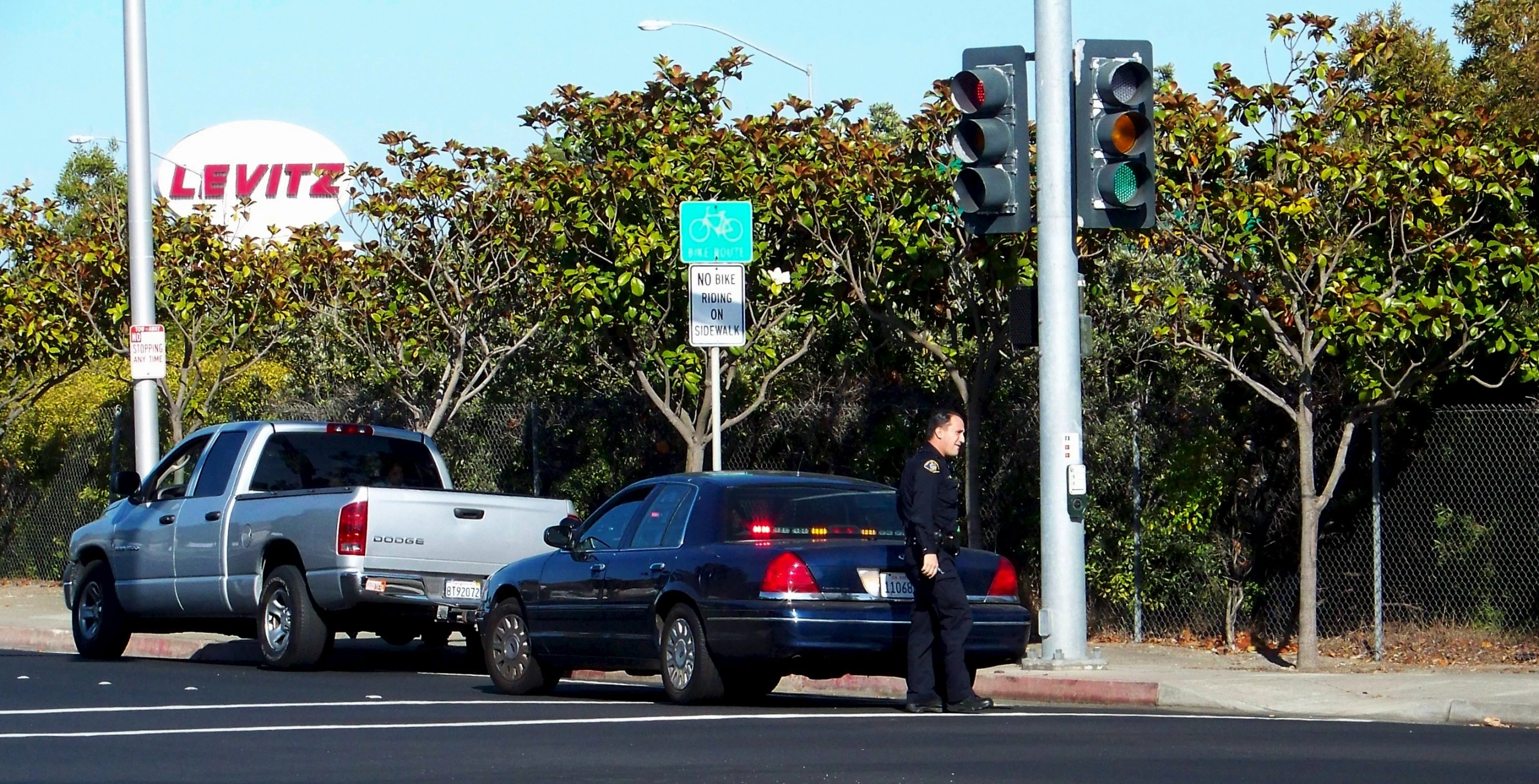 a man standing at a red light beside two cars