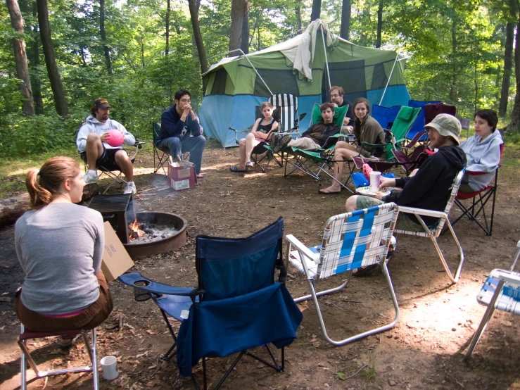 an outdoor area with a group of people relaxing around a campfire