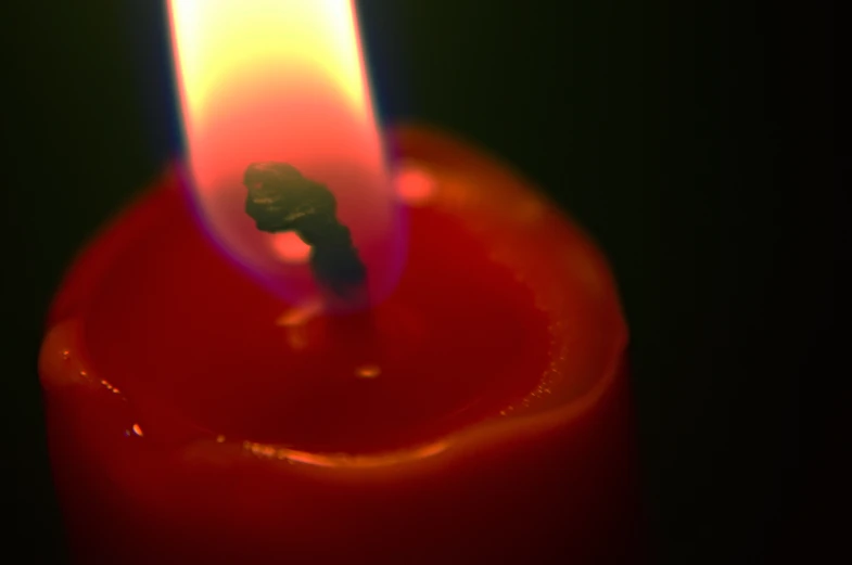 a red candle with a white flame lit up