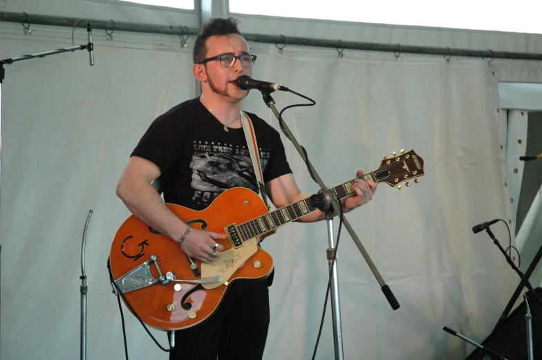 a man with glasses singing and playing guitar