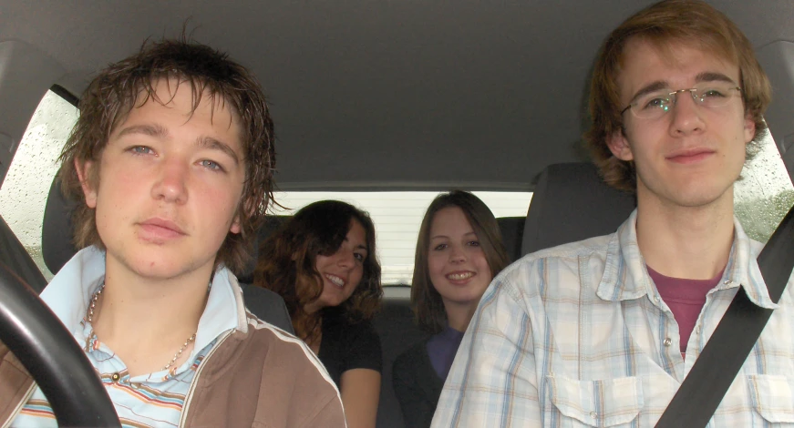 four young people are sitting in the back seat of a car