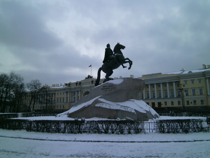 a statue of a man on a horse standing in the snow
