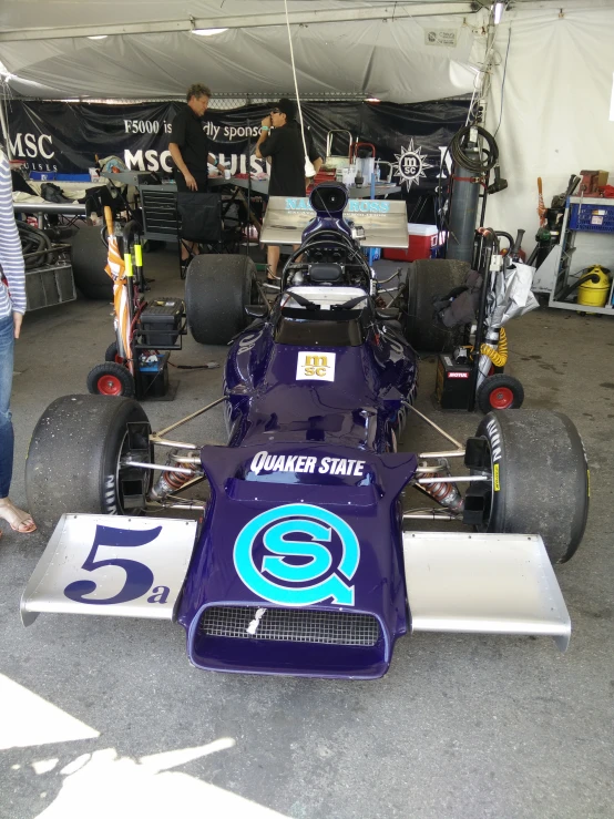 a couple of people are standing in front of a race car