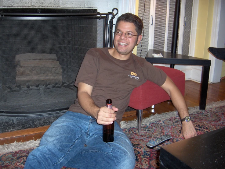 a man holding a beer bottle while sitting on the floor