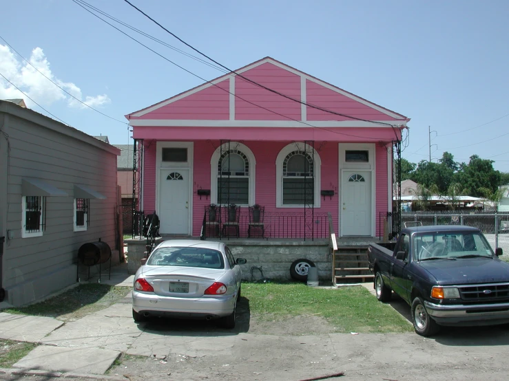 three cars are parked in front of a pink house