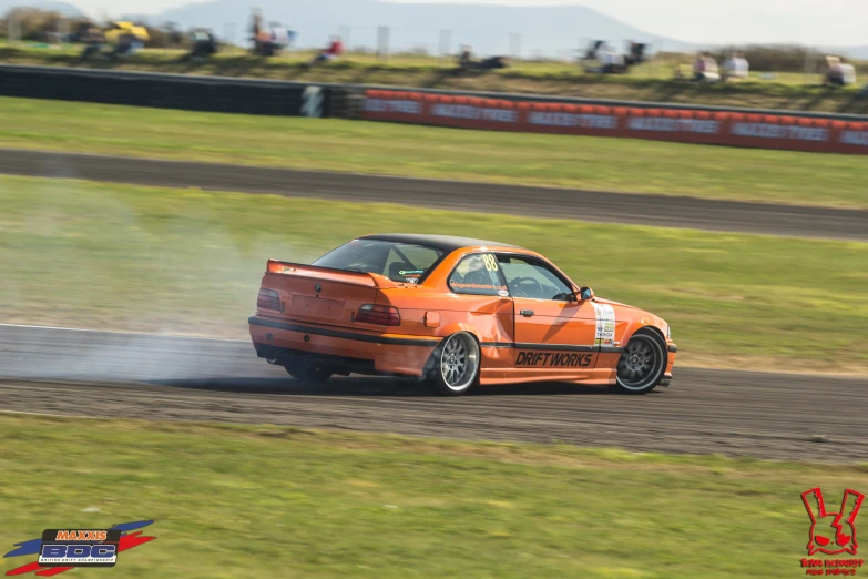 an orange car drifts down a track