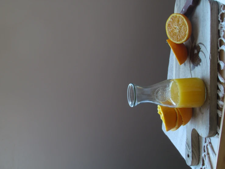 an orange cut in half next to a bottle of juice