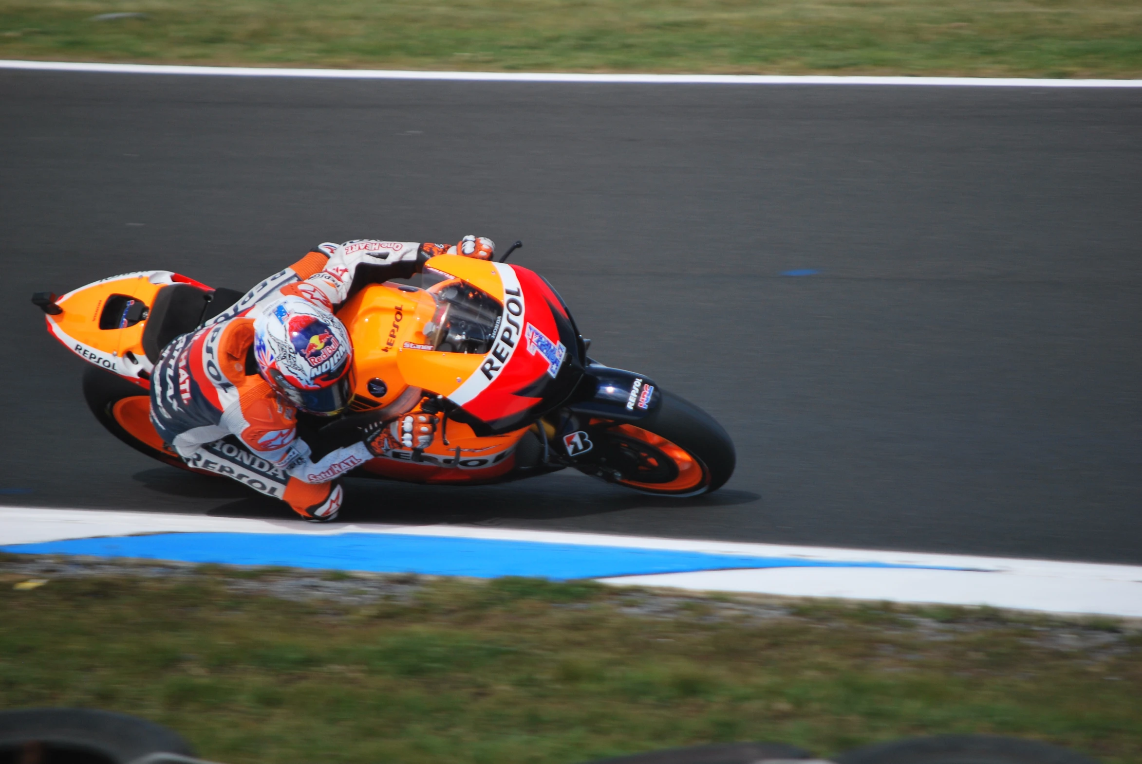 a motorcycle racer leans down on a race track