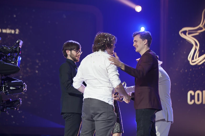 a group of people standing on stage with one man clapping