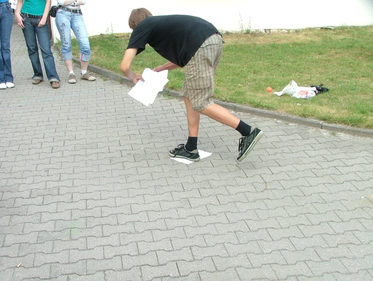 a man bending over on the ground as people stand nearby and look at him