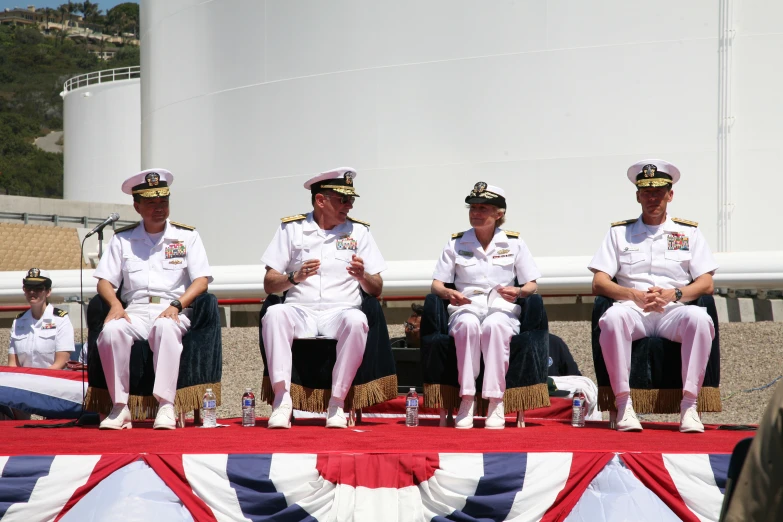 a group of military men in dress uniform sitting on a stage