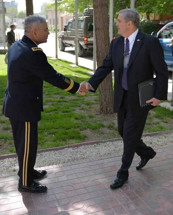 two men in navy uniforms shaking hands