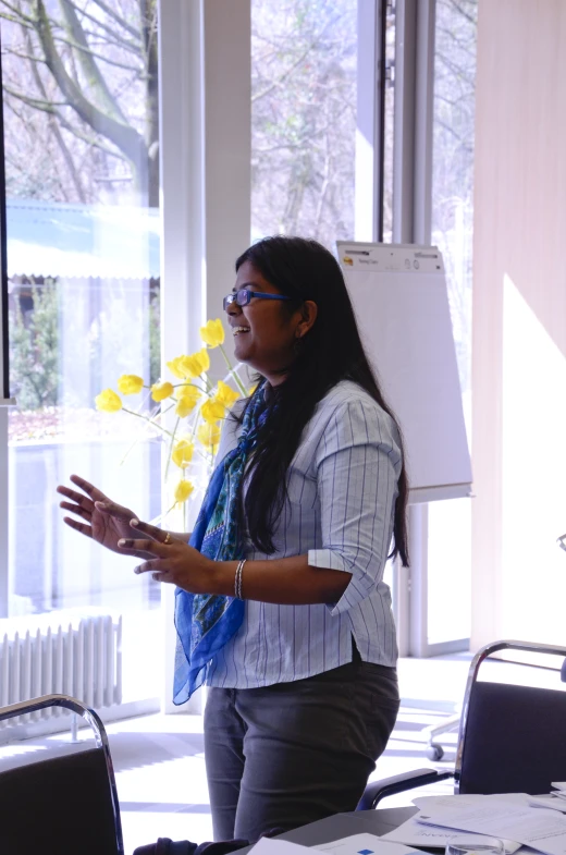 a woman in glasses with a tie holds flowers