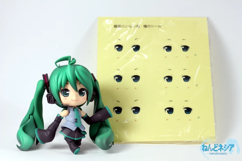 a doll with green hair sitting next to some papers