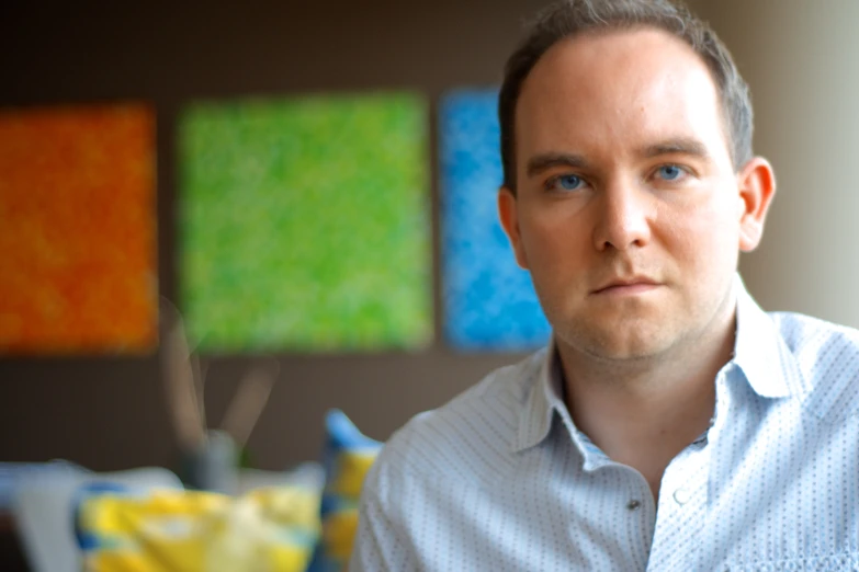 a man standing in front of some art on the wall