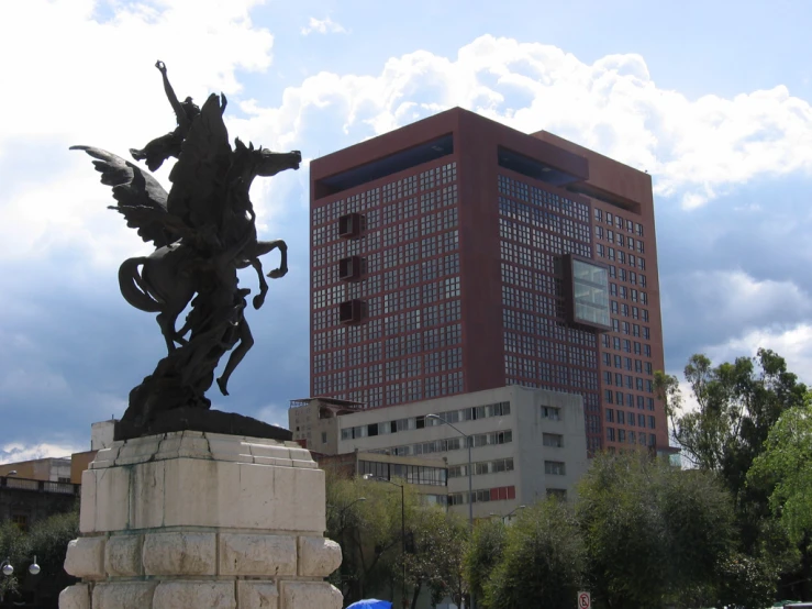 the statue of an insect is in front of a large brick building