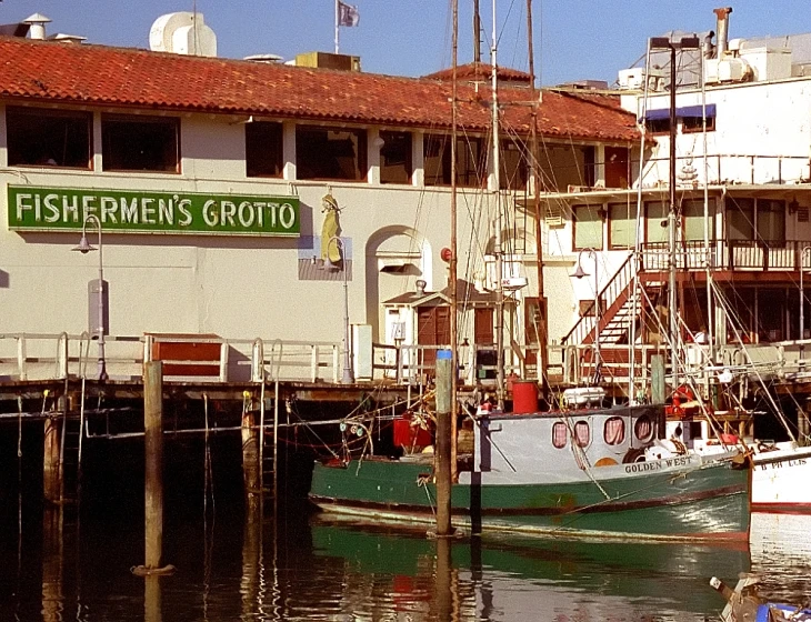 a white building with a green and red boat docked in front